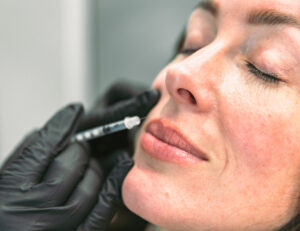 A close-up a photo of a woman who smiles as a provider injects Botox, an alternate wrinkle treatment to microneedling in Burlington.