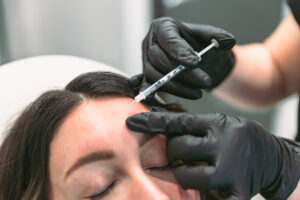 A close-up of a patient receiving an injection in her forehead before she receives crow's feet Botox shots in Burlington.