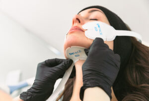 Two hands in black gloves place applicators on a patient's face as a part of treatment with Emface near Ocala.