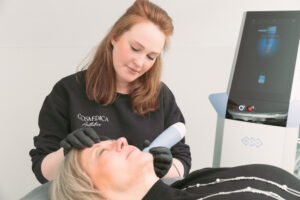 A provider with red hair administers microneedling in Burlington for a patient with short blonde hair.